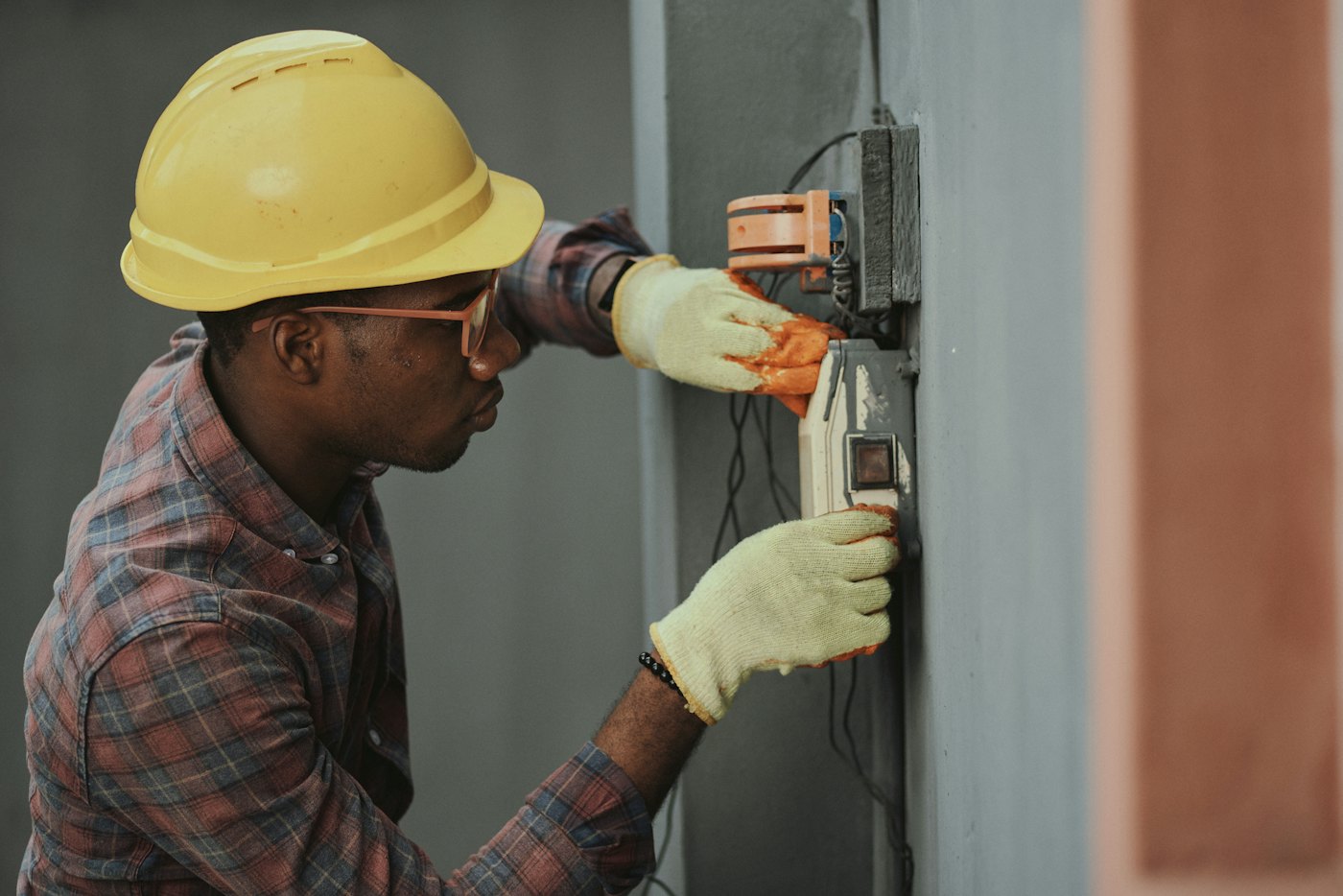 Electrician in a hard hat testing an electrical panel