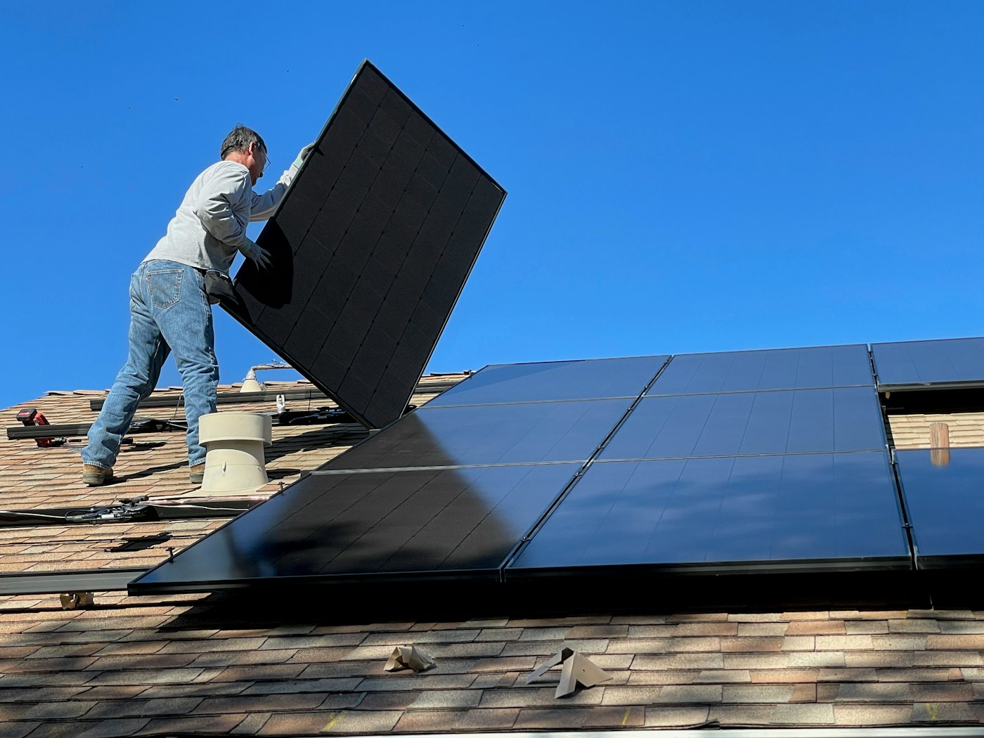 Installer fitting a solar panel onto a residential roof